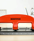 Red Three Hole Punch With PaperPro EZ Squeeze Technology Delivers 20 Sheet Capacity No Jam Action on a desk
