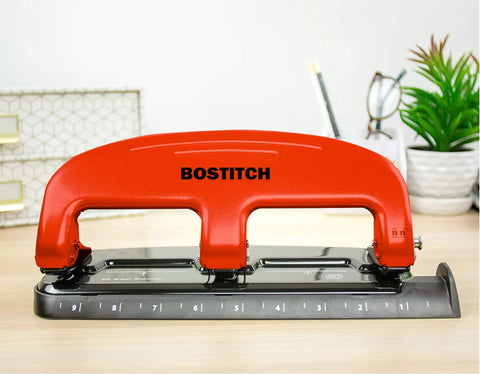 Red Three Hole Punch With PaperPro EZ Squeeze Technology Delivers 20 Sheet Capacity No Jam Action on a desk
