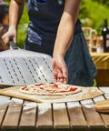 Person using Perforated Aluminum Pizza Peel 12 Inch With Long Handle Lightweight Rectangle Turning Spatula Paddle For Oven Transfer