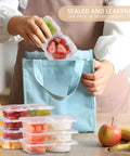 Person placing filled Two Compartment Snack Containers with Lids for Meal Prep into a blue bag, showing stacked containers with fruit.