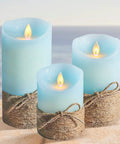 Ocean Blue Flameless LED Pillar Candles Set Of 3 With Remote And Timer, on a sandy beach backdrop.