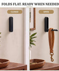 Sick Folding Wall Hooks Black Rounded Design Swivel Arms Tuck Flat Against Wall Space Saving Zinc Alloy, one open with leather strap.