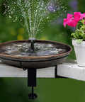 Deck Mounted Bird Bath With Detachable 12 Inch Bowl Thats A Breeze To Clean 0.7 Gallon Capacity Metal Bird Bath For Railings Balcony Fence Outdoors Adjustable Clamp Fits 0.5 To 3.5 Inch with water spray on railing next to pink flowers