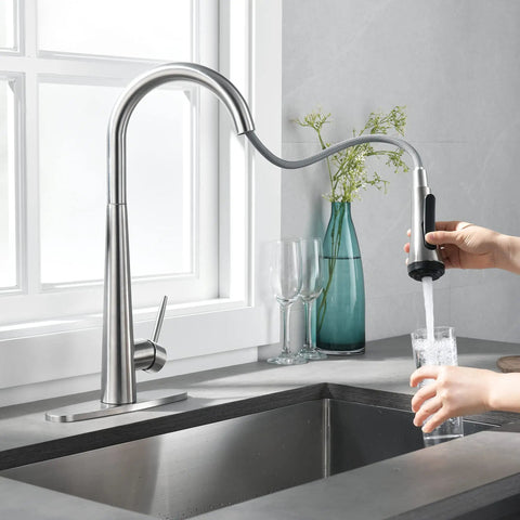 High Arc Kitchen Faucet With Pull Down Sprayer Single Handle Sink Faucet In Brushed Nickel next to a hand filling glass with water