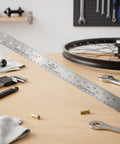 Top Shelf Stainless Steel Bike Spoke Length Gauge And Nipple Size Ruler For Cotter Pins And Bearings Dead On 360Mm double sided ruler on a workbench.