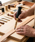Hand using Adjustable Heavy Duty Leather Hole Punch Set With Sturdy Wooden Handle And Six Precision Brass Tips for crafting on leather.