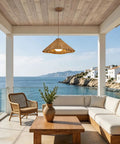 DLITISH 19'' Hand Woven Rattan Pendant Light with Glass Shade hanging over a coastal patio with ocean view.