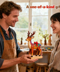 Man and woman smiling, holding a painted wooden reindeer sculpture in a workshop, labeled 'A one-of-a-kind gift'.