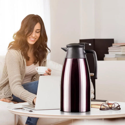 68Oz Ceramic Liner Thermal Carafe With Vacuum Insulation on table, woman in background with coffee, sleek design, 12h hot/24h cold