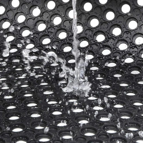 Heavy Duty Commercial Rubber Floor Mat Featuring Hexagonal Drainage Cutouts For Garage And Shop Kick Ass Non Slip Oil Grease Resistant Tough As Nails Level with water splashing on surface.