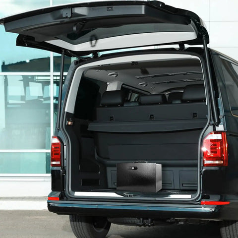Fireproof Document Safe Box With Dual Lock System placed in an SUV trunk, showing sturdy handle and portable design, black color