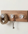 Crystal Clear Acrylic Dresser Knobs 20 Pack Diamond Shape Cabinet Knobs on wooden board, holding belt and key.