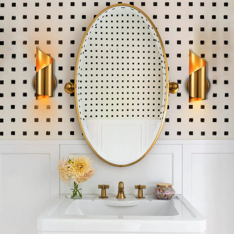 Gold Brass Wall Sconces Set Of Two Modern Two Light Vanity Lights flank oval mirror in bathroom with black and white wall tiles.