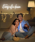 Couple in front of 'It Was All A Dream Neon Sign LED Wall Decor 27 By 8.5 Inch Timed Dimmable Neon Lights' in cozy setting.