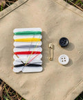 Go-To 200 Piece Mini Travel Sewing Repair Kit with threads, buttons, and a safety pin on a fabric surface.