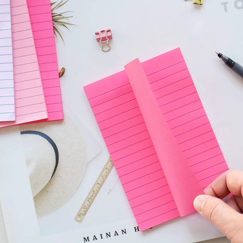Person turning page of 9 Pack 4x6 Lined Sticky Notes With Super Sticky Adhesive, Pink Themed Colorful Post It Notes on desk
