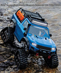 Blue RC off-road truck with roof rack, LED light bar, and oversized knobby tires on rocky terrain