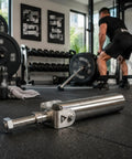 Stainless steel barbell holder with swivel base in home gym setup, near weightlifting area, barbell in use behind the holder.