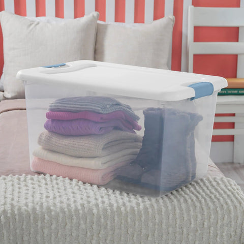 64 Quart Clear Latching Storage Boxes 4 Pack With White Lids, filled with folded sweaters, on a bed for organization