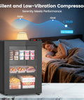 2.3 Cu Ft Upright Mini Freezer With Tempered Glass Door And Flexible Temp Control Keeps Your Stash Ice Cold In This Hella Compact Unit beside a sleeping woman.