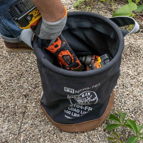 Flame-Resistant Canvas Tool Bucket in use, showing leather-reinforced handle, filled with tools, 100-pound load rated.