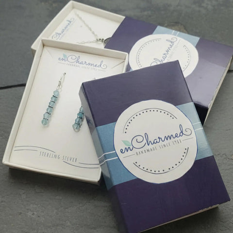 Sterling silver jewelry in packaging box featuring earrings and enCharmed logo