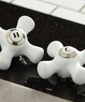 Close-up of polished white cross handles labeled hot and cold for Governor Two Handle Deck Mount Bar Faucet In Oil Rubbed Bronze