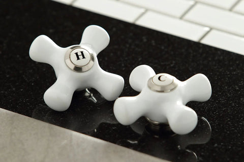 Close-up of polished white cross handles labeled hot and cold for Governor Two Handle Deck Mount Bar Faucet In Oil Rubbed Bronze