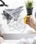 Person assembling F-15 Fighter Jet Metal Model Kit for Adults, DIY 3D Puzzle to Build at Home, with detailed metal sheets.