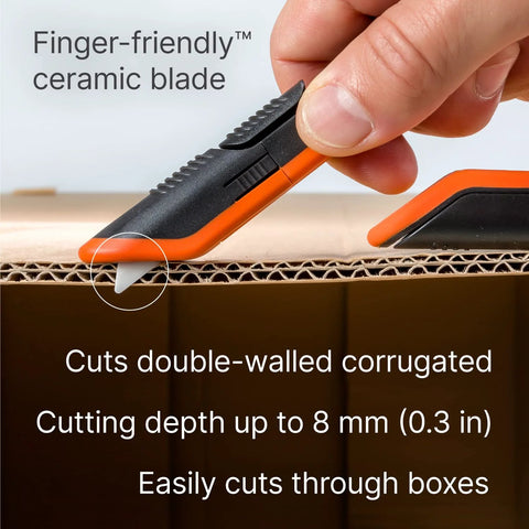 Slice box cutter with orange and black handle and ceramic blade cutting cardboard.