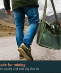 Person walking with green musette bag holding geology tools kit including rock pick hammer chisels magnifying glass for fieldwork.
