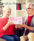 Senior couple exchanging gift box labeled 'Best For You' with festive background, 'Best Gift for Plant Lover' text overlay.