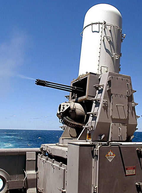 Close-up of 20mm Phalanx CIWS on ship deck, showing cannon and radar with ocean background.
