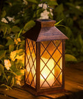 14 Inch Solar Lanterns Outdoor Garden Lights Weatherproof Waterproof LED Flickering Flameless Candles For Patio Table Yard Party Auto On At Dusk With A Lit Warm Glow And All Night Battery Life angled view on outdoor table.