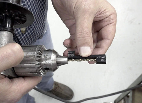 Person holding drill with GM LS III Manifold Drill Template Kit for easy bolt removal and hole hopping, showing depth gauge.