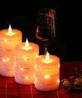Three Pack Pink Real Wax Flameless Taper Candles With Lifelike Flickering LED Flame And Surrounding Fairy Lights on a table