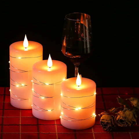Three Pack Pink Real Wax Flameless Taper Candles With Lifelike Flickering LED Flame And Surrounding Fairy Lights on a table