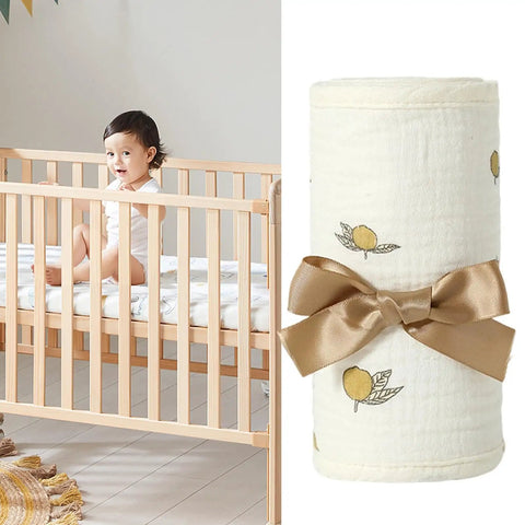 Child in crib next to rolled Bed Rail Teething Protector for sides and corners, breathable cotton gauze cover with bow.