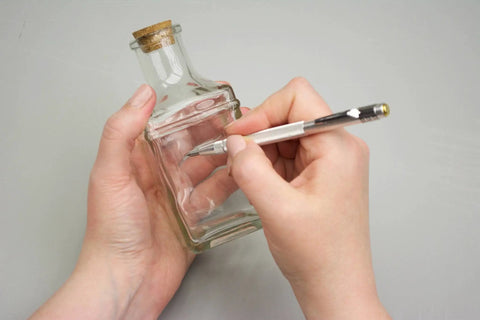 Person using Heavy Duty Tungsten Carbide Scriber Engraving Pen on a glass bottle, marking for crafting projects.