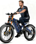 Hardened Dual Motor Electric Bike delivering 50 mph peak velocity, with a rider on a full suspension blue frame, 26-inch wheels.