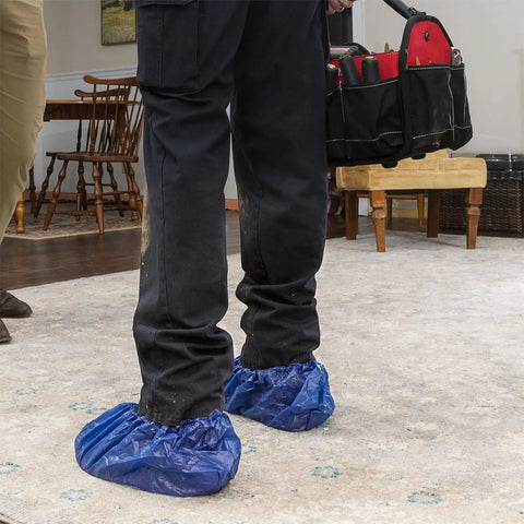 Person wearing dark blue Waterproof Shoe Covers Disposable Non Slip Extra Large Boot Covers 40 Pairs for wet weather inside a home