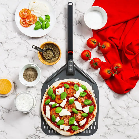 Perforated 12 Inch Pizza Peel, Metal Pizza Turner For All Ovens, Indoors and Outdoors Use, with a pizza and ingredients on marble countertop.