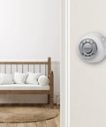 Round No Frills Non Programmable Manual Thermostat with Easy Dial Control in a cozy home setting, wall-mounted near a wooden bench.