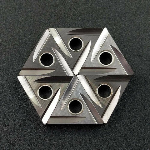 Top-down view of six TNMG carbide turning inserts with center holes, hexagonal arrangement, silver finish
