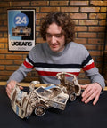 Endurance Racer DIY Model Car Kit 3D Puzzle, Dope Mechanical Wooden Sports Car For Adults To Build One Twelfth Scale, Vintage 1960s Inspired Hobbyist Kit With Real Working Gears, Movable Parts, And Easy To Follow Instructions For First Time Builders. man assembling 1:12 wooden race car model
