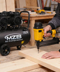 Top Notch 13 Point 2 Gallon Air Compressor Featuring Dead Silent Oil Free Pump And Heavy Duty Steel Tank Delivering Rock Solid 115 PSI for powering a nail gun on wood.