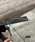 Hand holding a Tartan AAA Welding Electrode One Eighth Inch Diameter For Mild Steel Repairs against a welded metal surface.