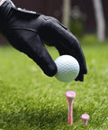 Golfer placing ball on Bold Bamboo Golf Tees Set With 50 Painted Tees And 10 Extra Short 1.5 Inch Range Tees, visible pink tees