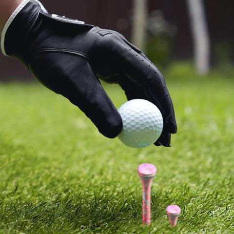 Golfer placing ball on Bold Bamboo Golf Tees Set With 50 Painted Tees And 10 Extra Short 1.5 Inch Range Tees, visible pink tees