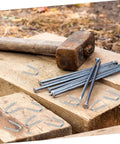 50 Pack U Shaped Fence Staples For Quick Install And Strong Hold Durable Metal Garden Stakes on wooden surface with hammer